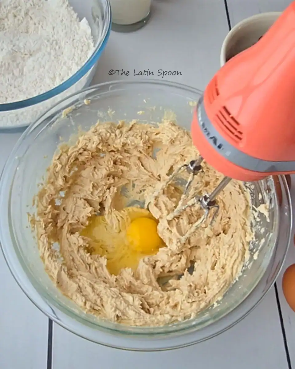 A glass bowl showing the mixture of butter and brown sugar with a freshly added egg, while the mixer is turned off.