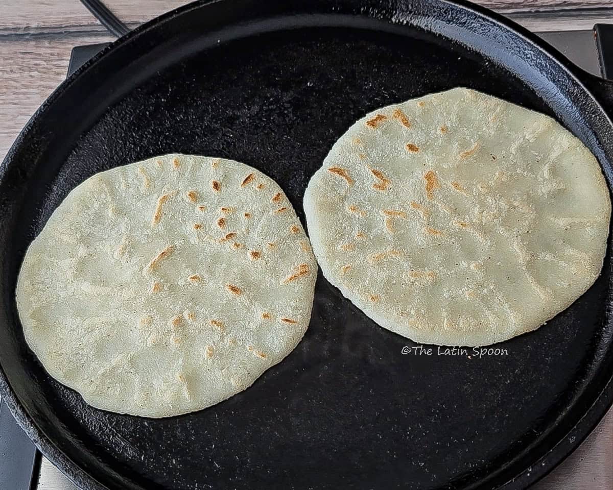 Two tortillas cooking on the top side, ready to be flipped and puff up