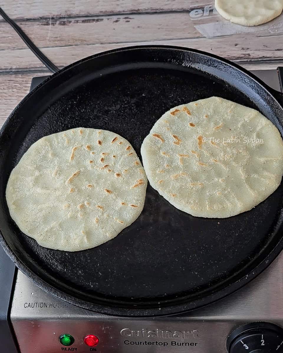 Two tortillas cooking on the top side, ready to be flipped and puff up
