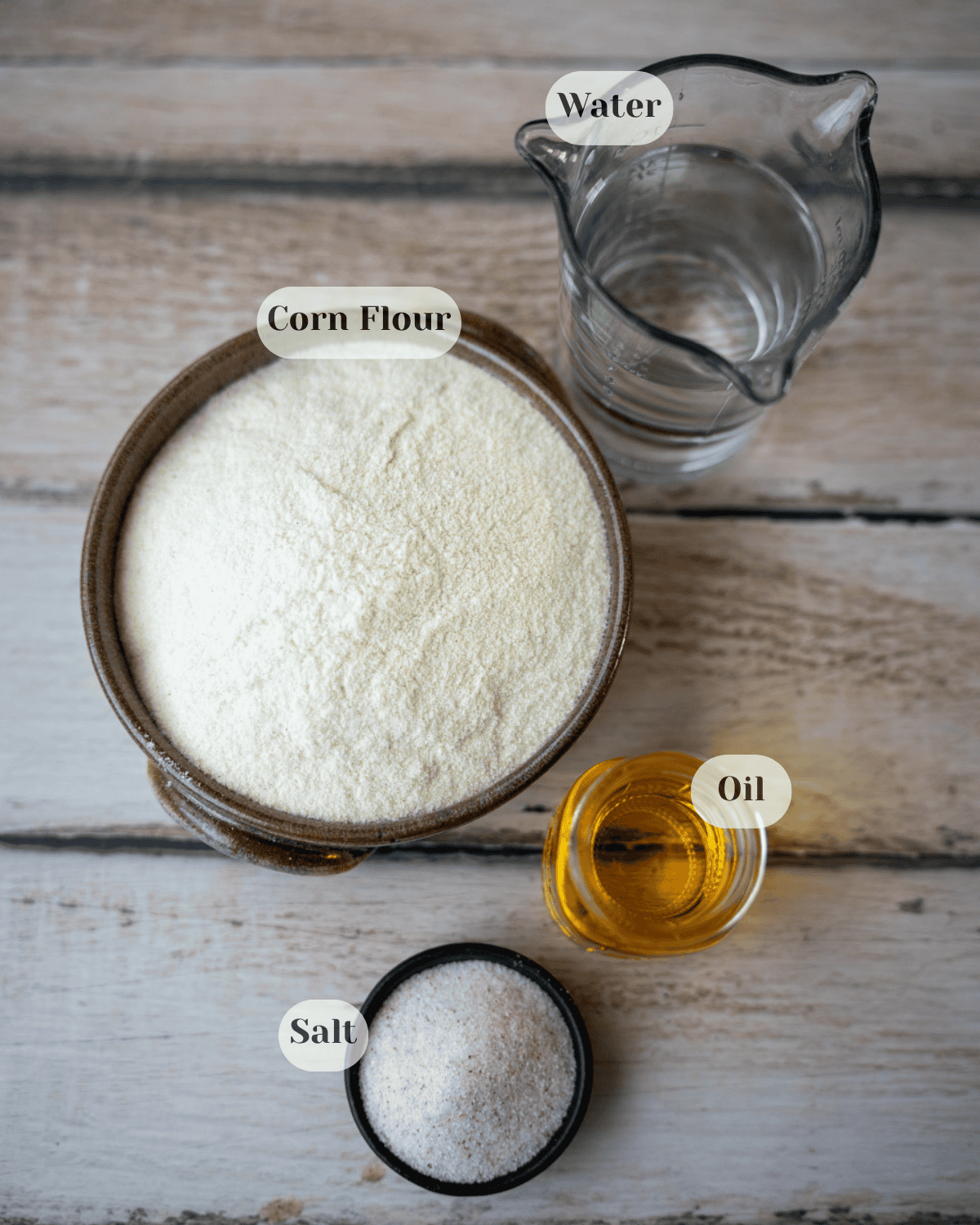 Top view of a container with water, a bowl with corn dough, a small jar with oil, and a small dish with salt