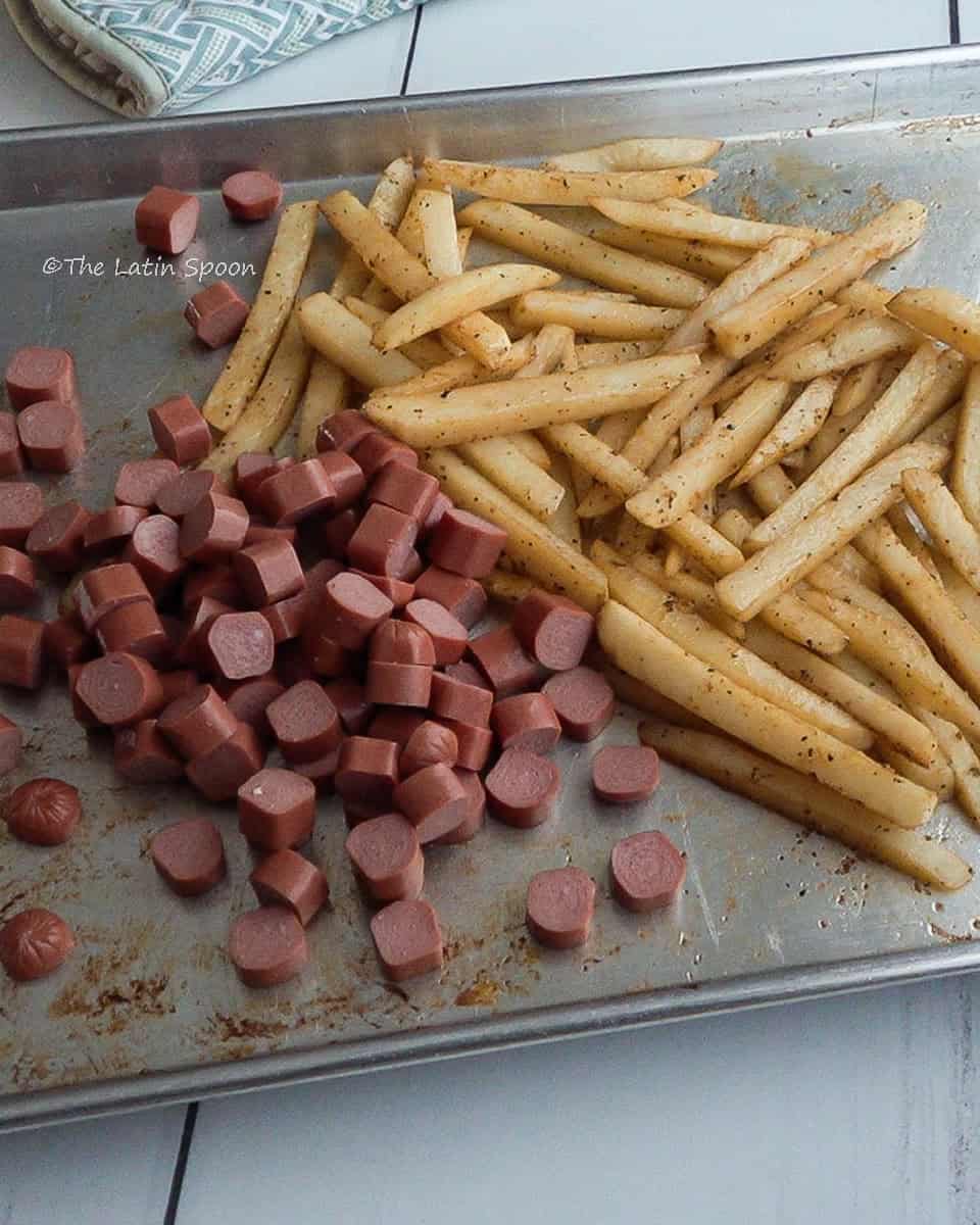 Lightly cooked potato strips on one side of the tray and sliced sausages on the other.