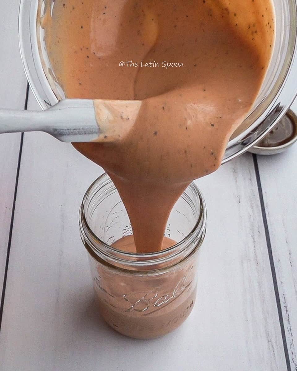 The tomato sauce mixture is carefully poured into a small jar.