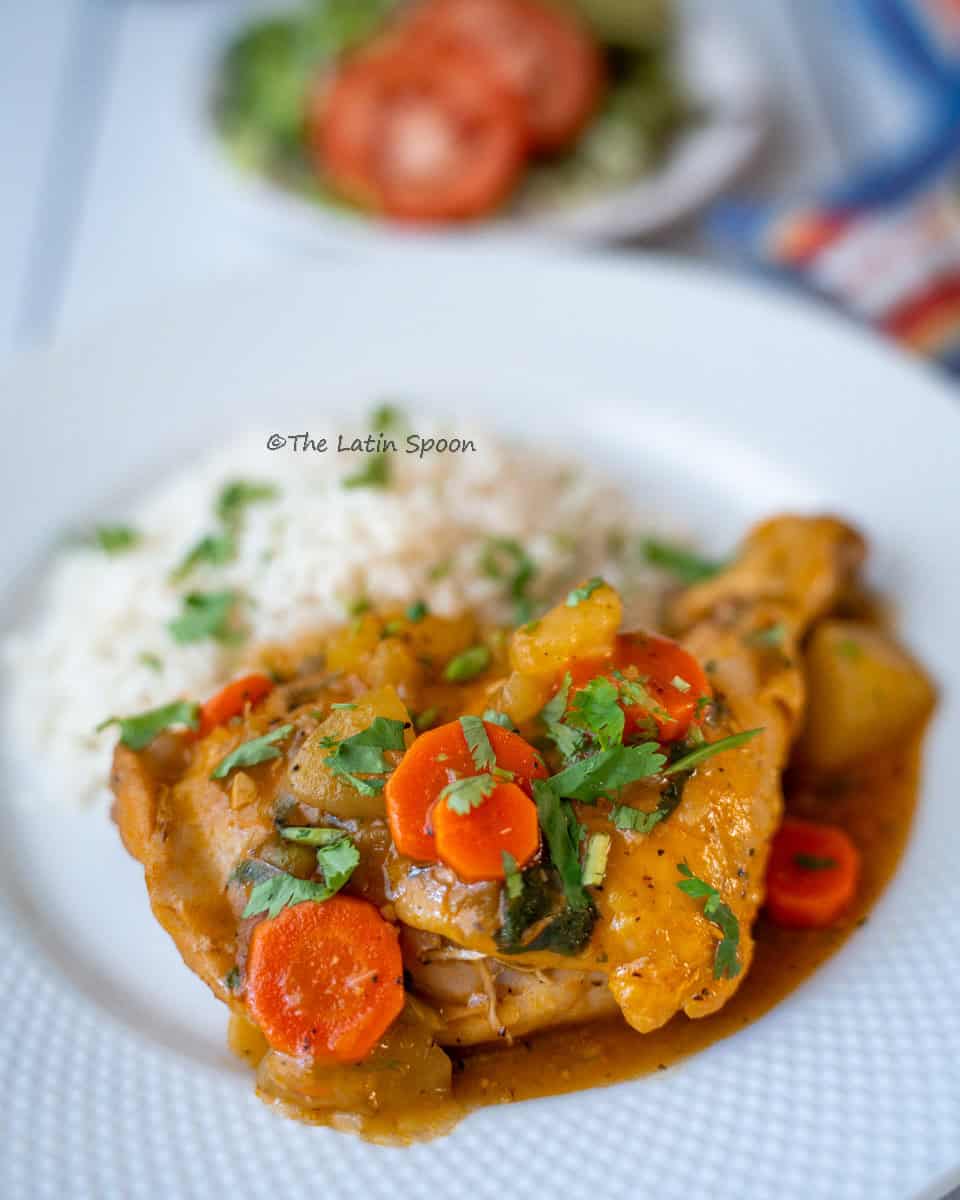 A plate with a piece of chicken and carrots, served with white rice and decorated with little pieces of fresh cilantro.