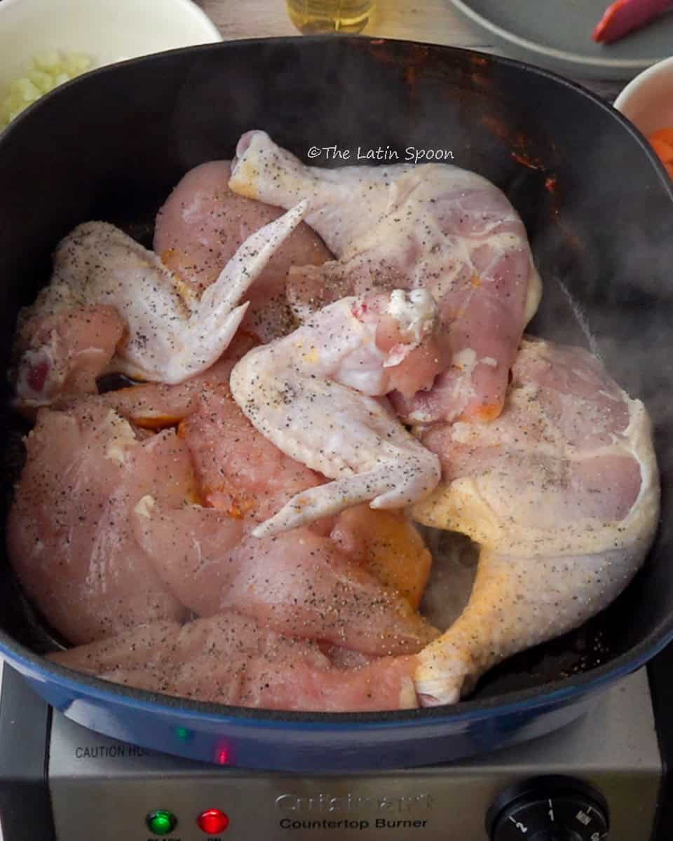A Dutch oven with the whole chicken cut into pieces