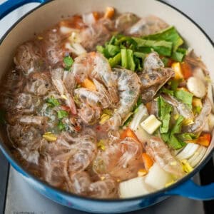 A pot containing shrimp shells and vegetables.