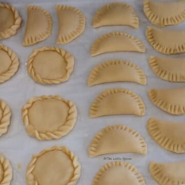 A tray of empanadas in different shapes is shown: some are round and others are half-moon shaped.