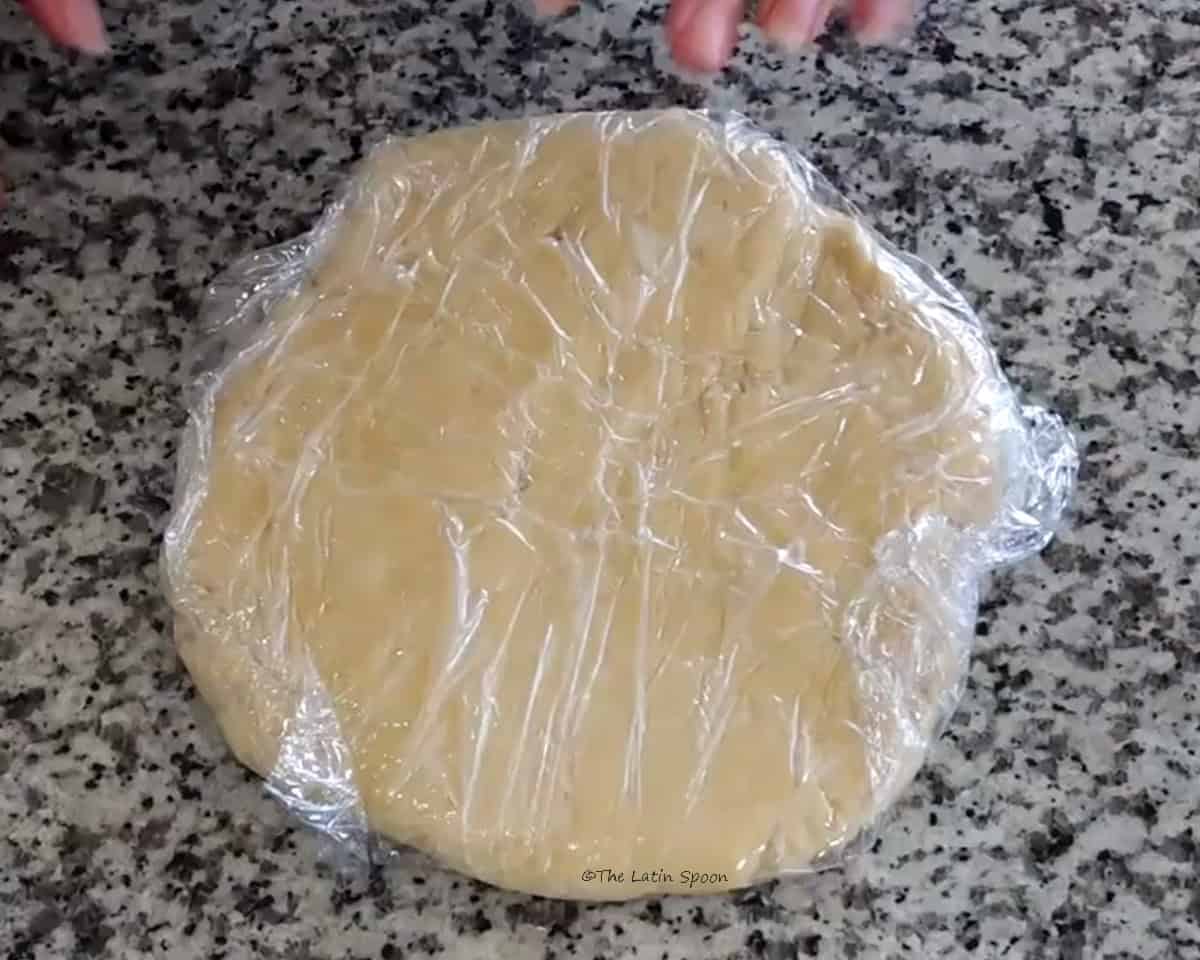 A ball of dough wrapped in plastic wrap is shown.