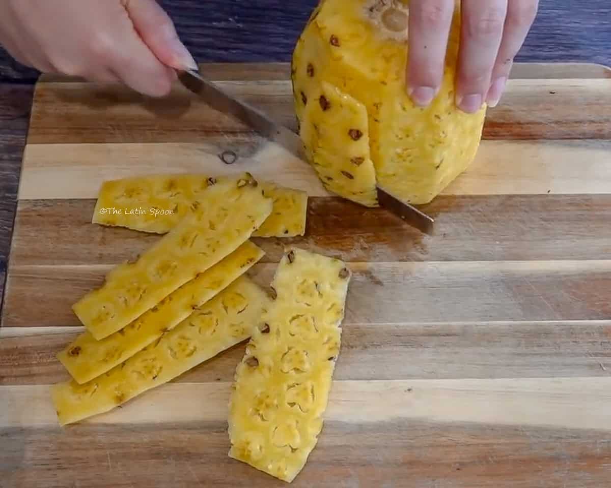 It shows that after removing the pineapple peel, another layer is being removed to take out the pineapple eyes.