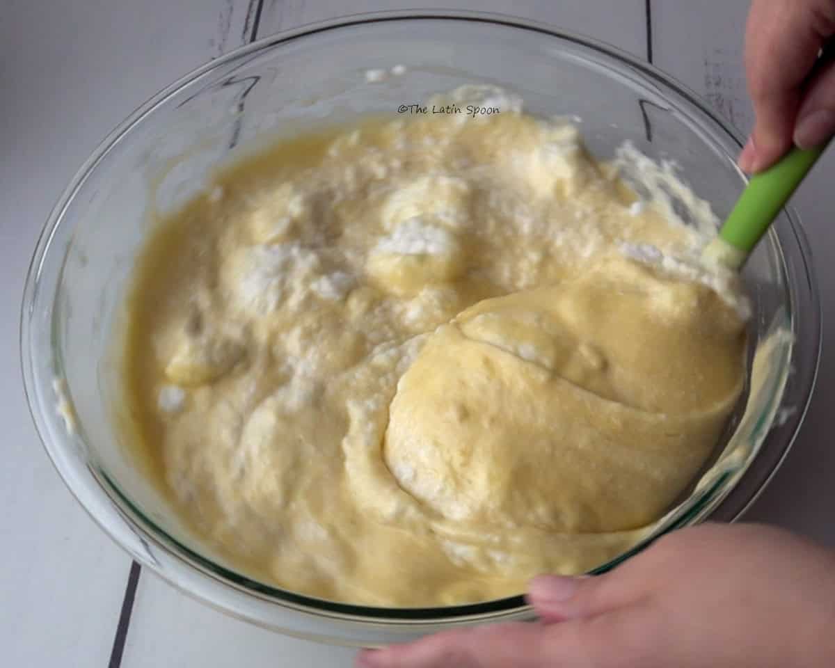 A spatula gently folds the whipped egg whites into the batter using slow, circular movements.