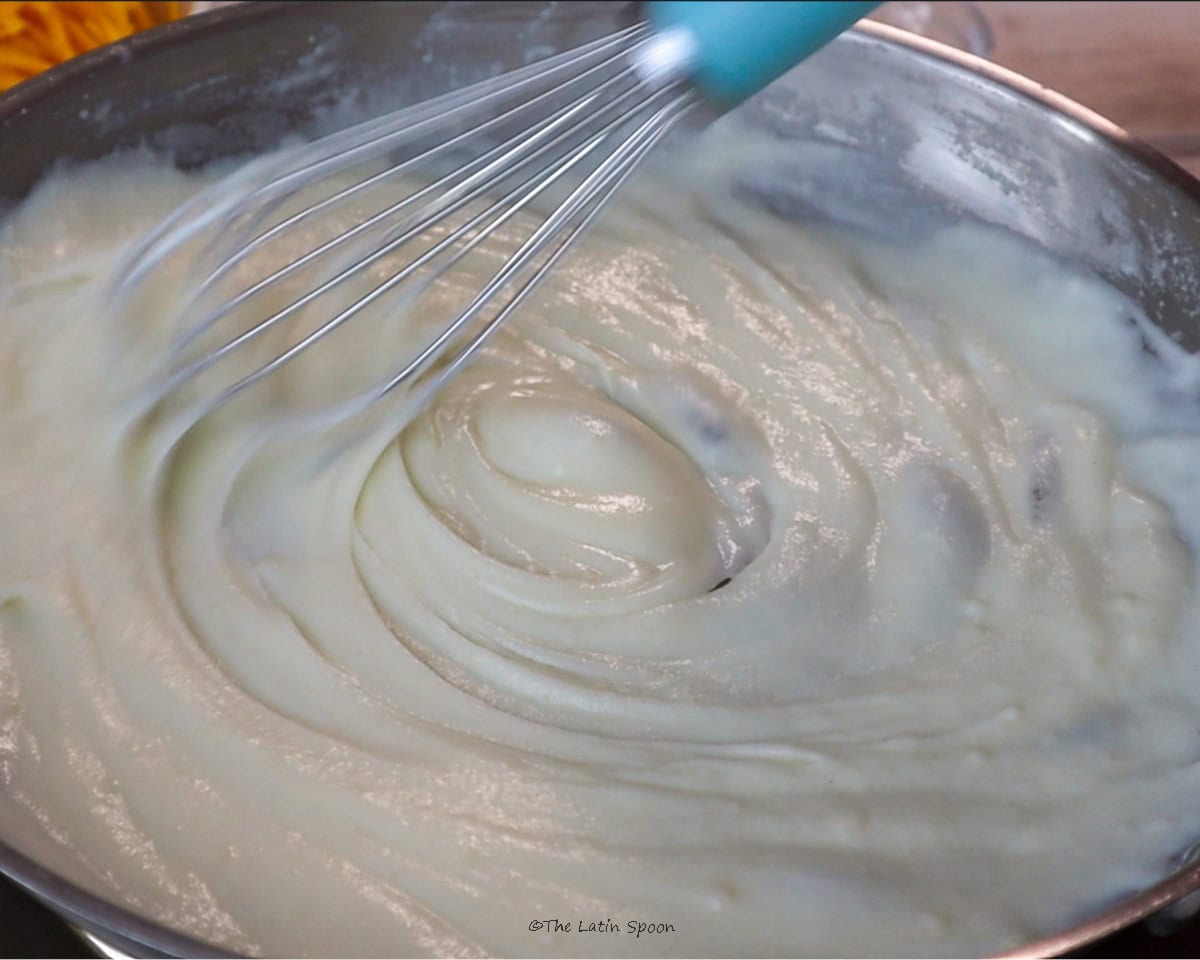 A thick mixture being stirred with a whisk.