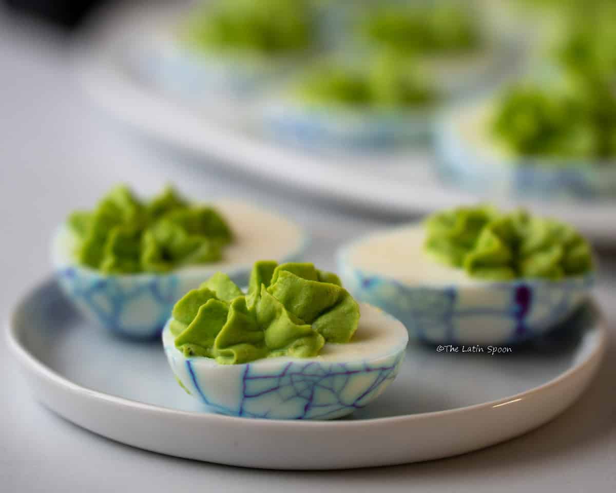 A plate with three filled Halloween deviled eggs.