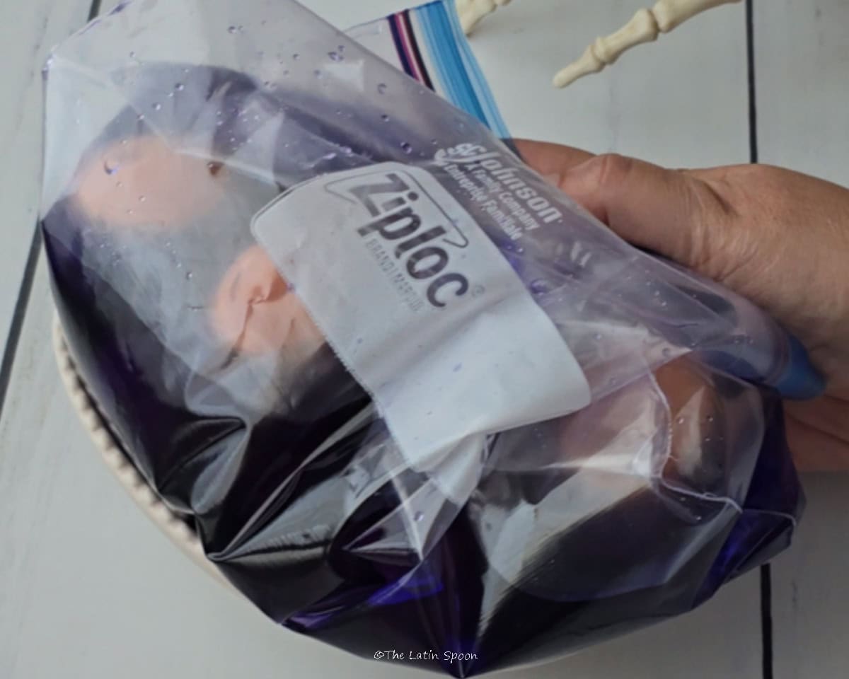 A hand holds a bag filled with eggs and colored water.